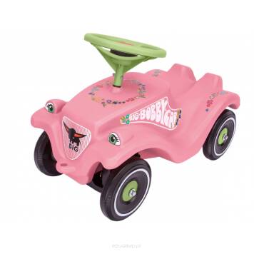 Jeździk w kolorze różowym został wyposażony w zieloną kierownicę z klaksonem